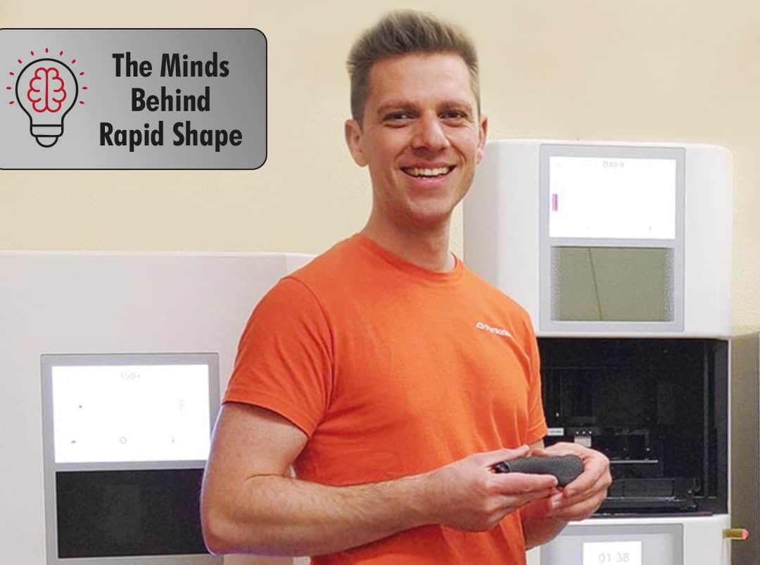A man in an orange shirt holding a remote control.