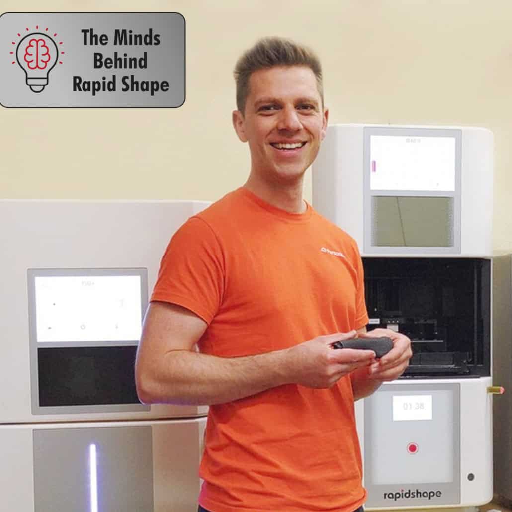 A man in an orange shirt holding a remote control.